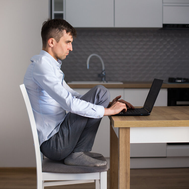 Jak dbać o zdrowie wykonując pracę siedzącą? Siedząc w różnych pozycjach. Daniel pracując często zmienia pozycje.